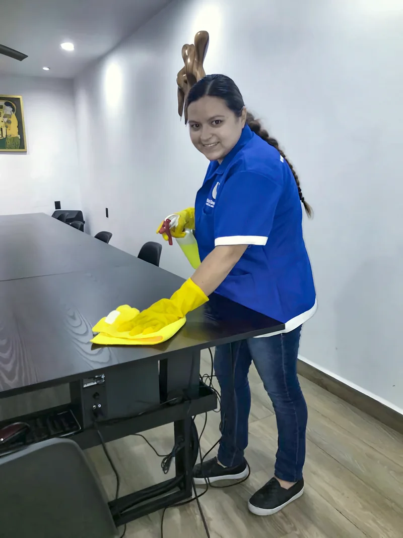 Personal de limpieza de Only Clean Office limpiando la mesa de una sala de juntas en una oficina de Guadalajara